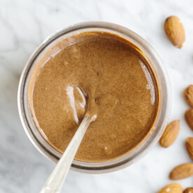 Almond butter in a glass jar with a spoon.