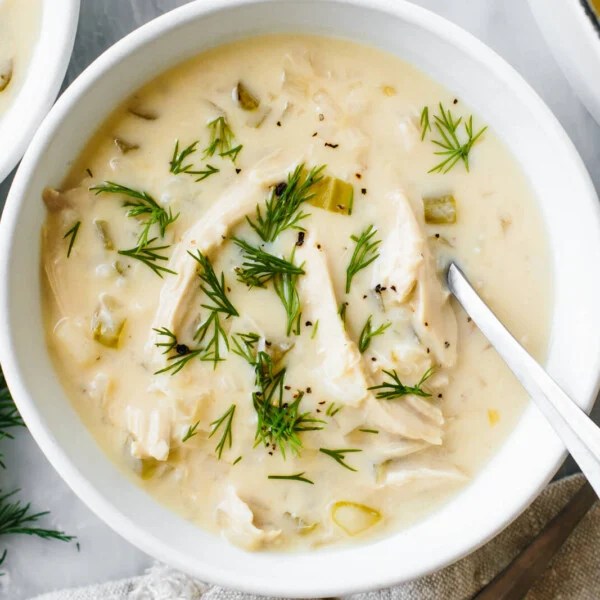 A bowl of Avgolemono soup next to dill