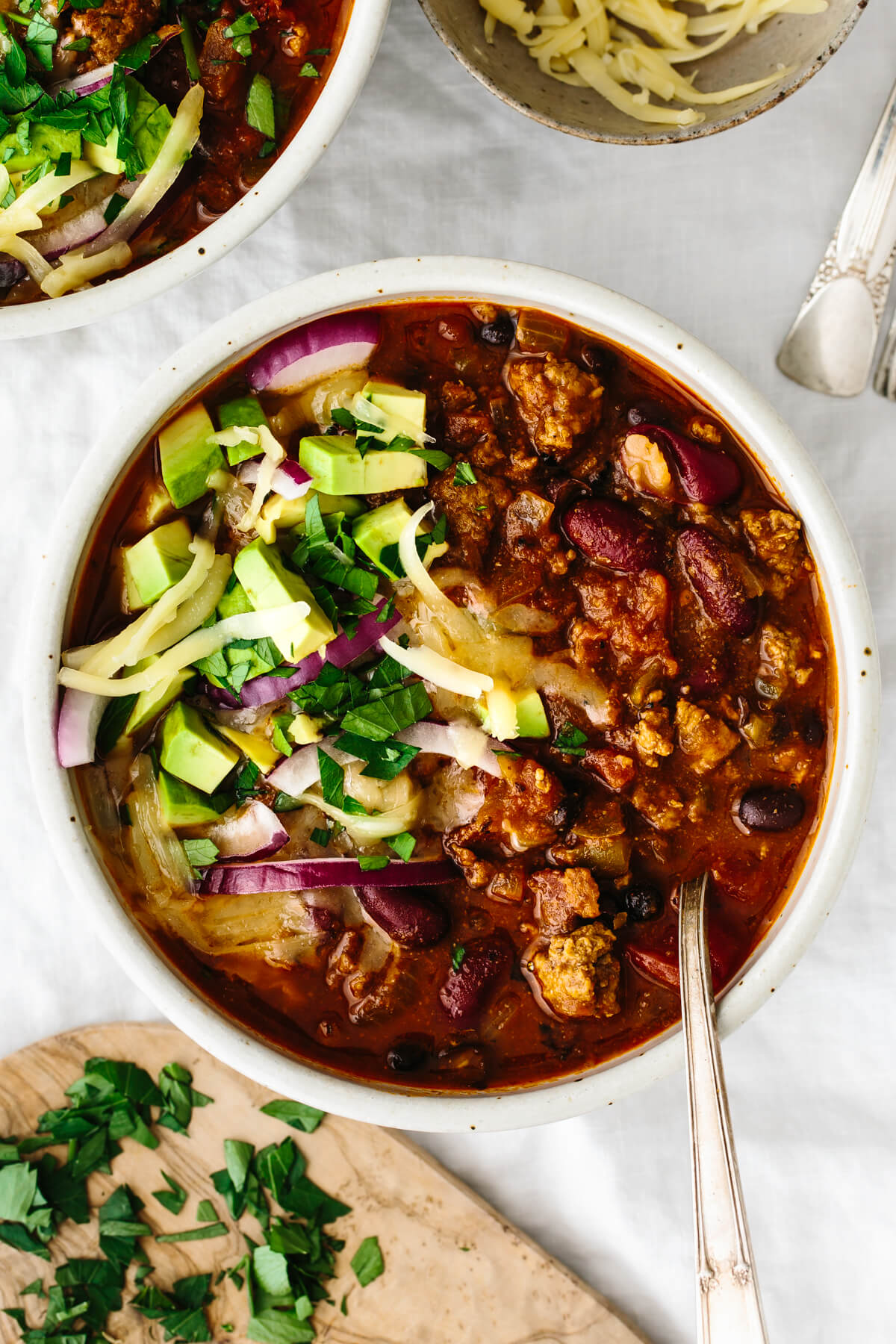 A bowl of chili on a table with a spoon.