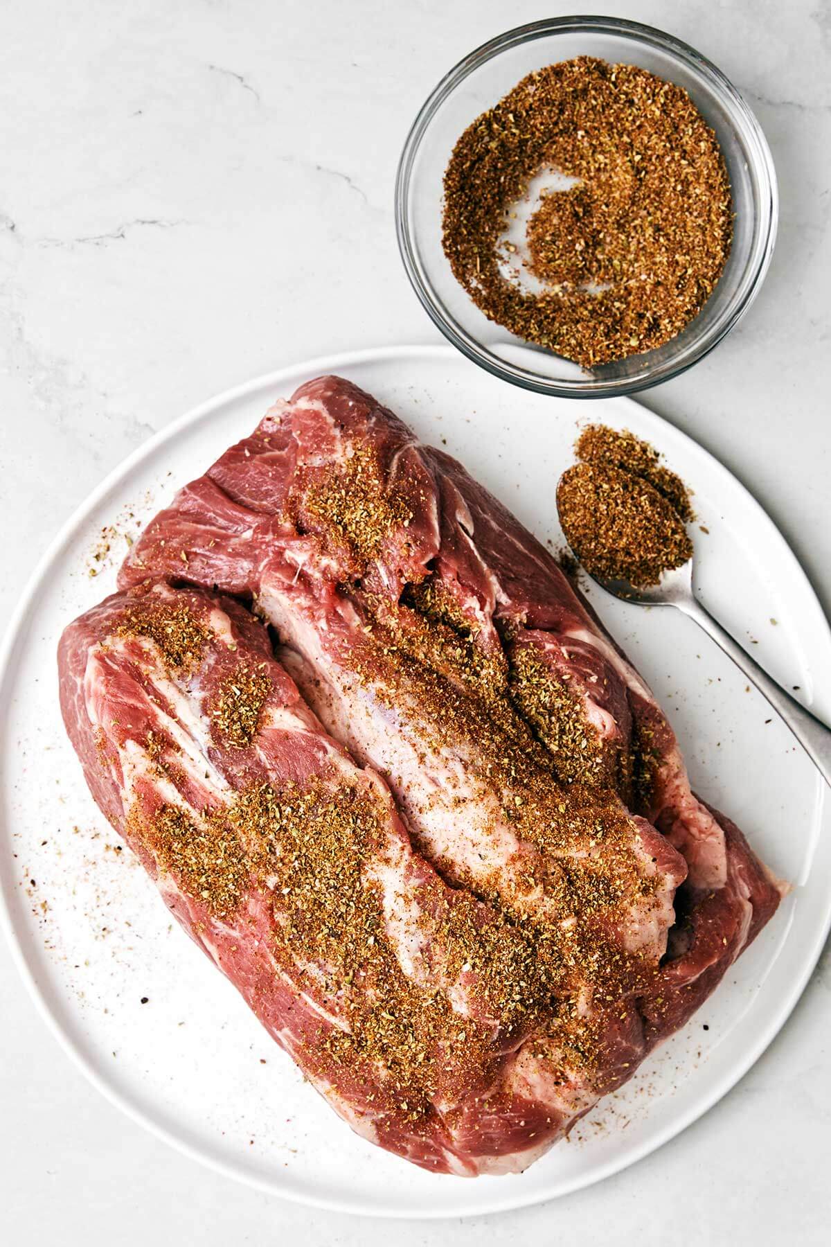 Adding seasoning to a pork shoulder.