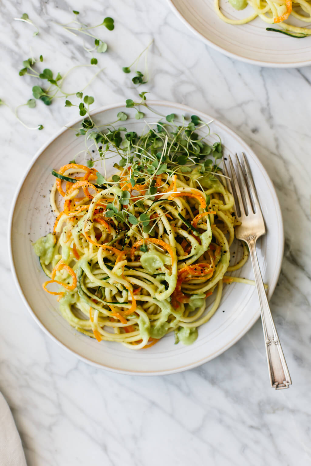 Carrot and zucchini pasta is mixed with a creamy, avocado cucumber sauce for a simple and delicious zucchini noodle recipe that's gluten-free, vegan, paleo and whole30.