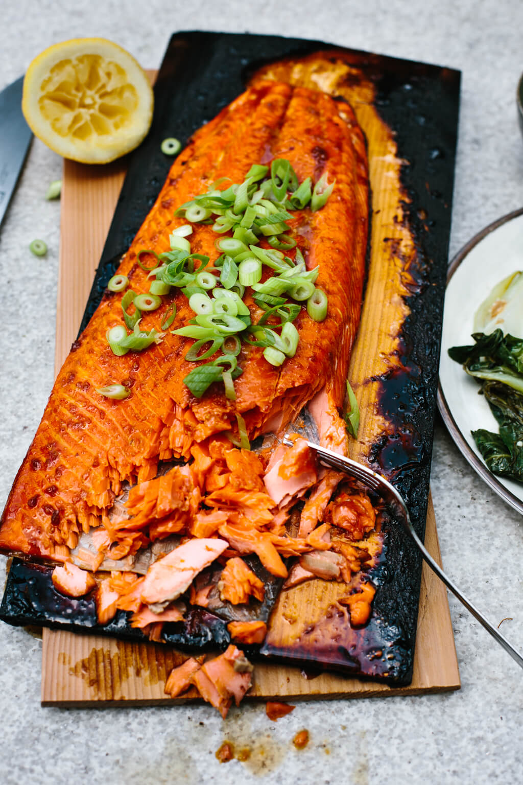 Salmon on a charred cedar plank garnished with green onions.