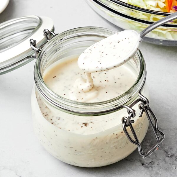 A container with coleslaw dressing and a spoon.