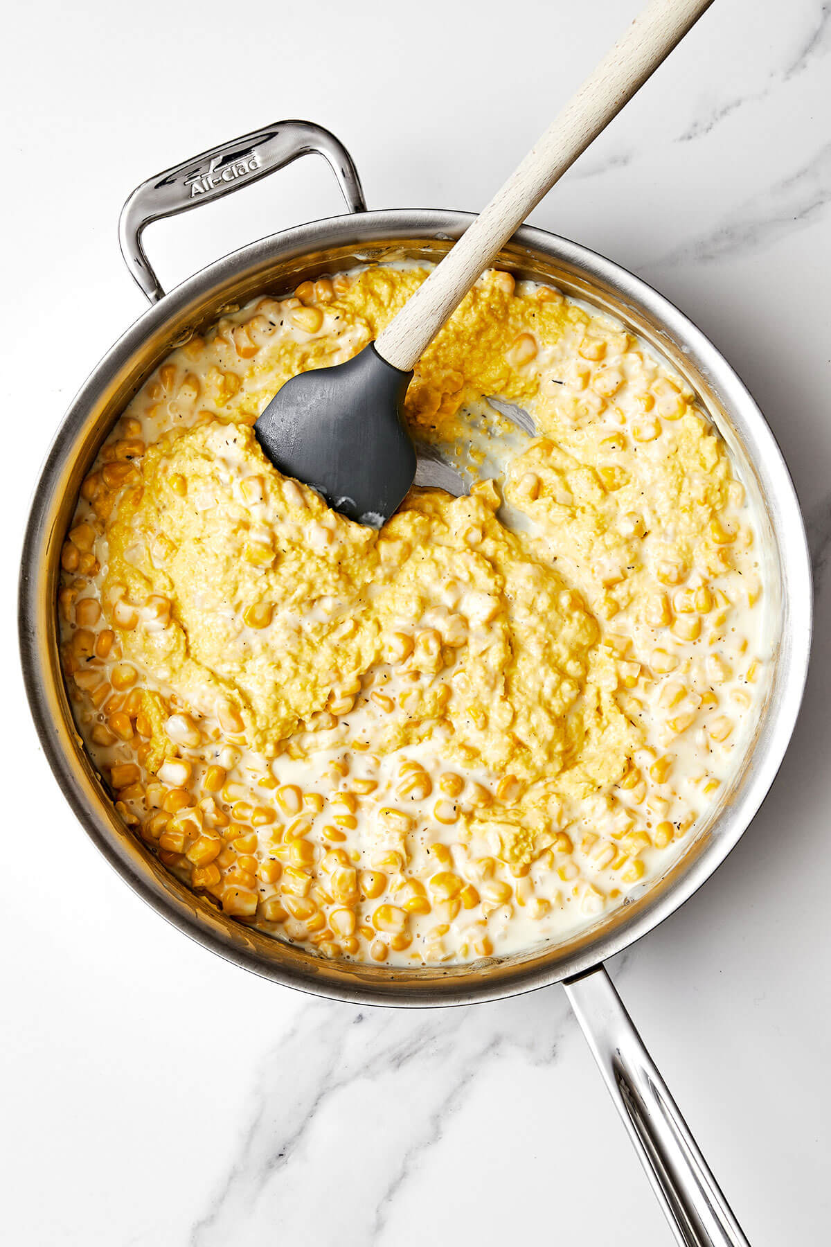 Creamed corn in a pan with a spatula.