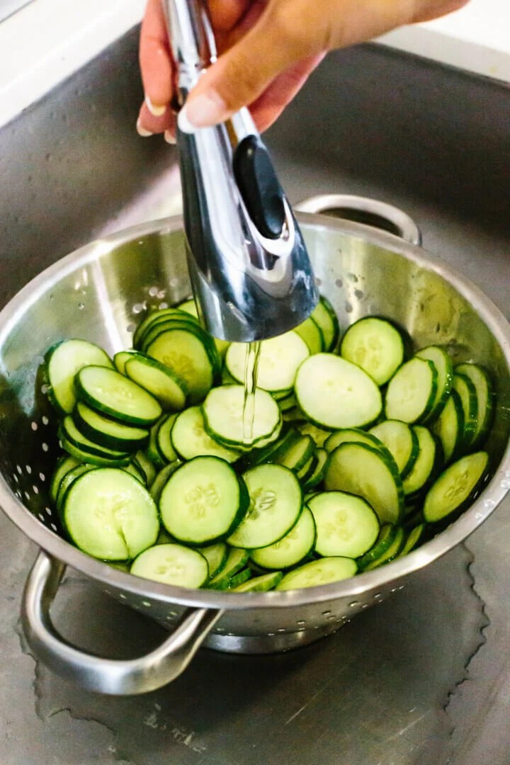 Rinsing cucumbers in a colander for a cucumber salad