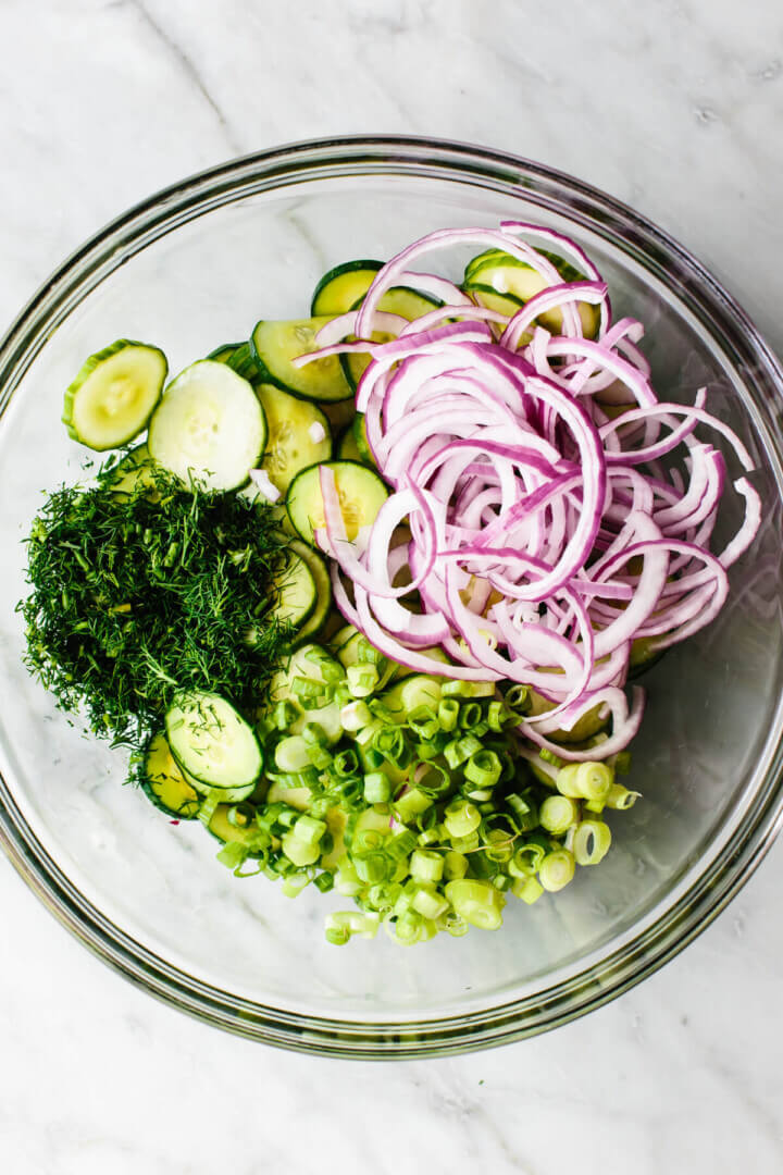 Mixing cucumber salad ingredients in a glass bowl