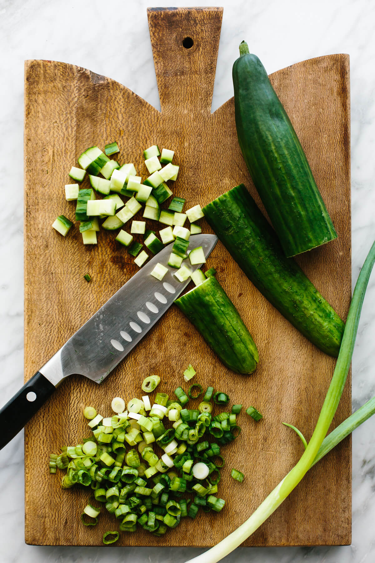 Diced cucumber and green onions on a board for cucumber shrimp salad