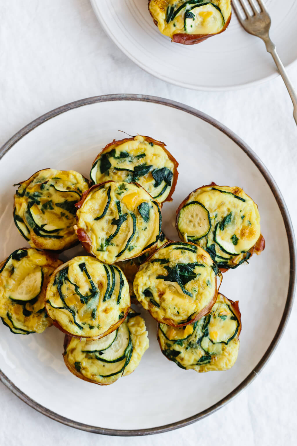 Plate of egg muffins with zucchini and prosciutto.