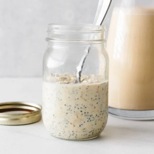 A jar of eggnog overnight oats with a spoon.