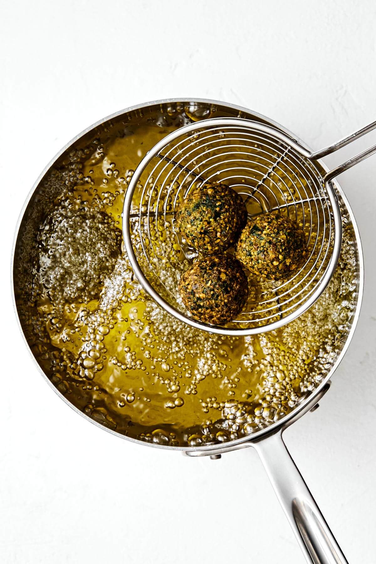 Deep frying falafels in a pot of oil.