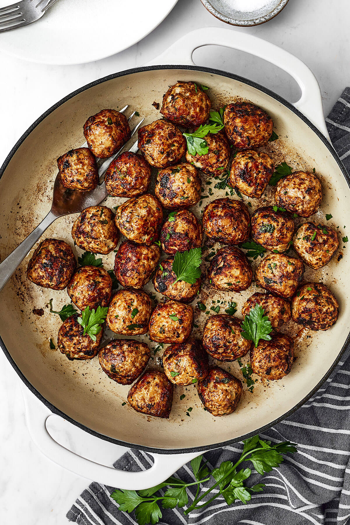 A white pan of fennel pork meatballs next to a napkin