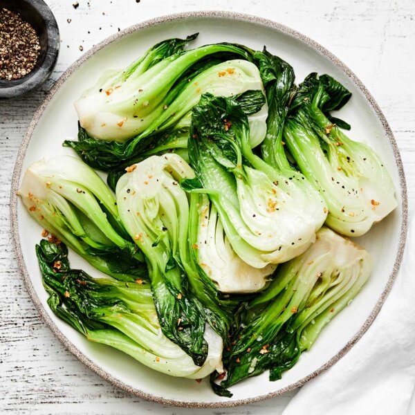 A white plate of cooked baby bok choy.