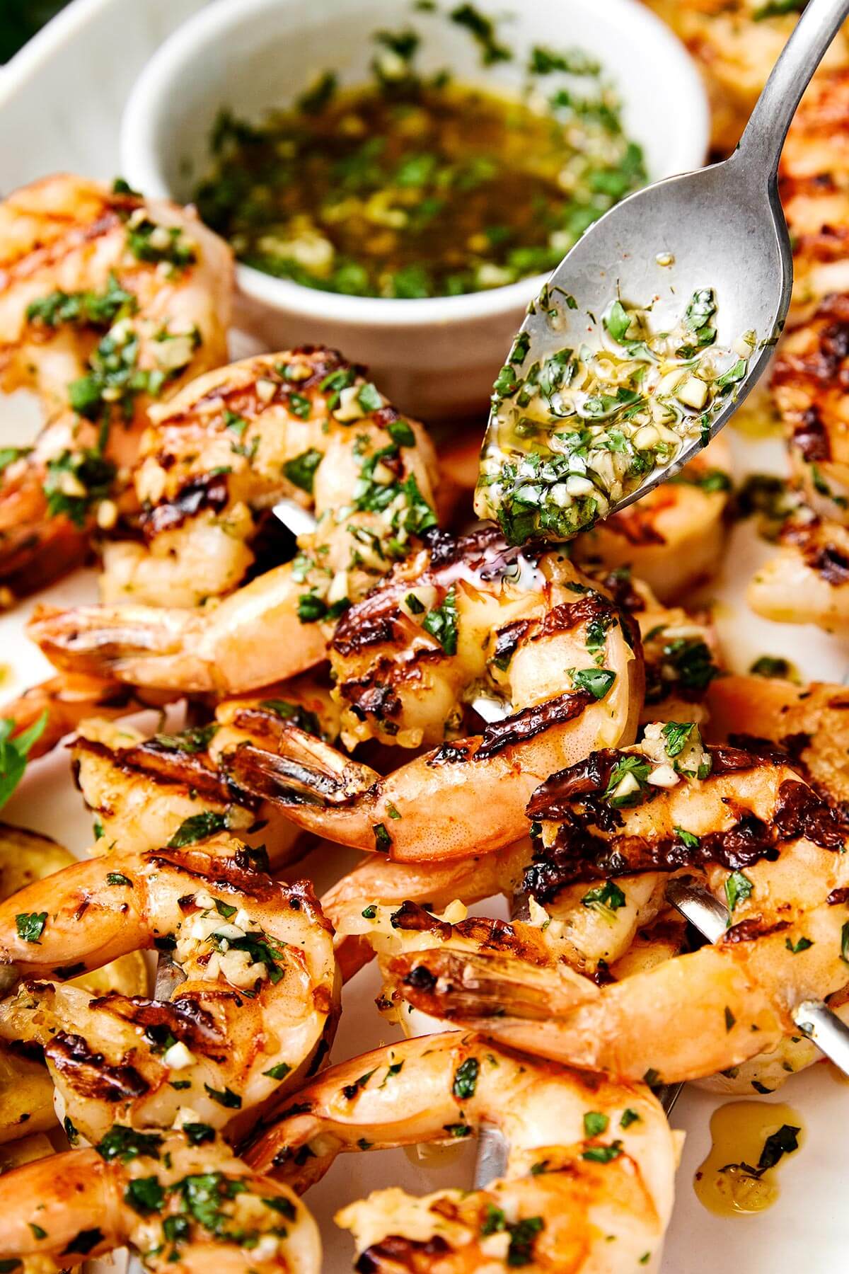 Pouring sauce over grilled shrimp skewers.