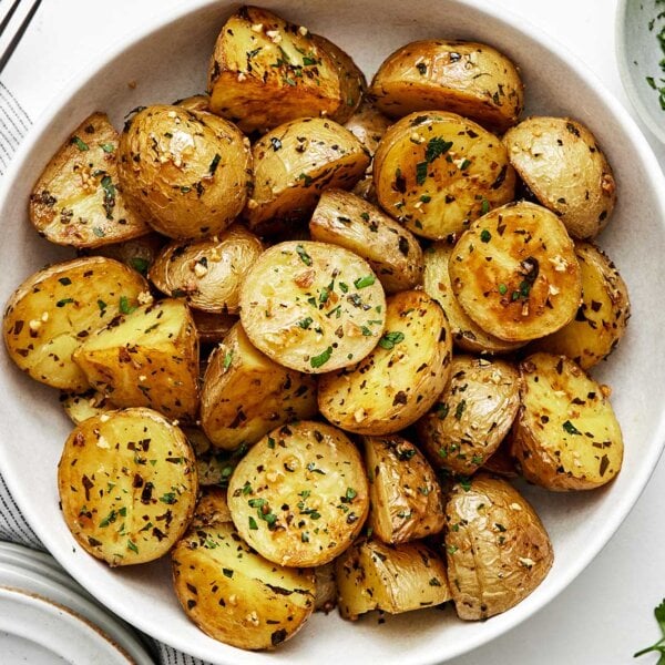 A white bowl of garlic roasted potatoes.