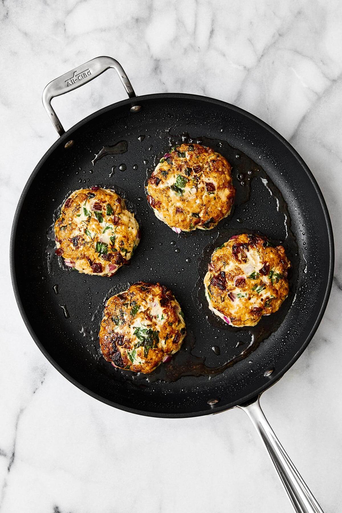 Pan frying Greek chicken burger patties.