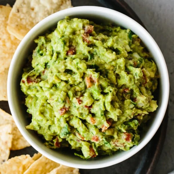 Guacamole recipe in a bowl next to tortilla chips.