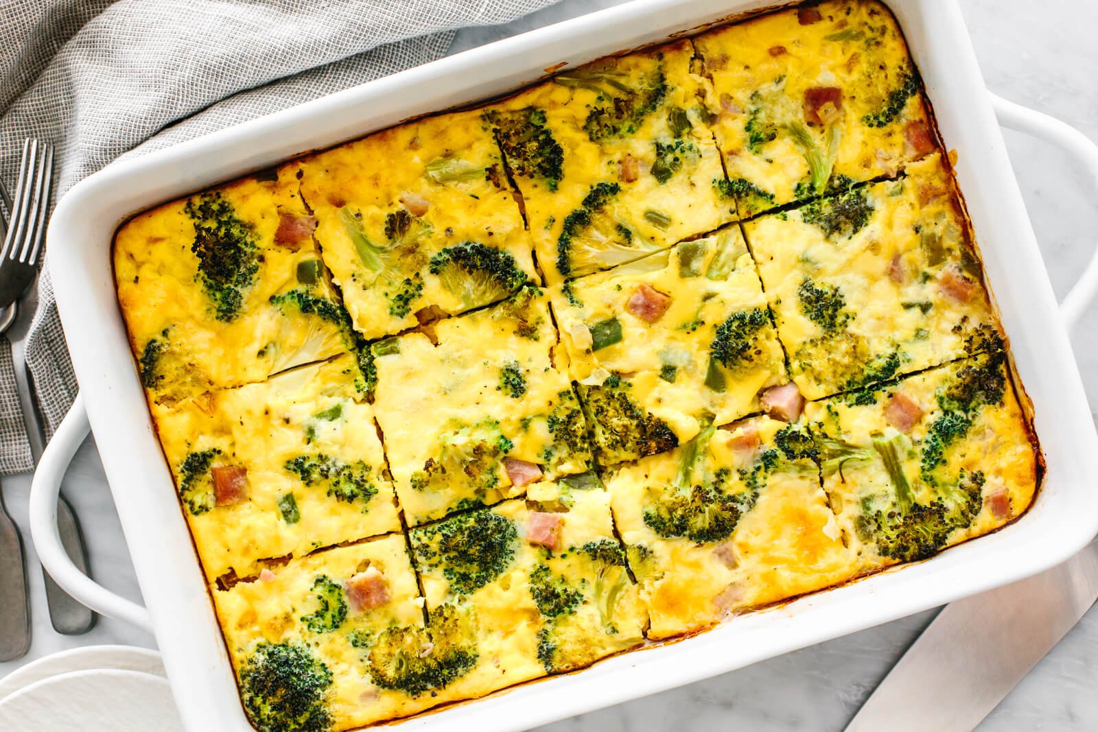 A white dish of ham and broccoli casserole