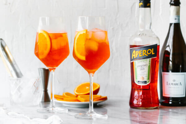 Glasses of Aperol Spritz next to a bottle of Prosecco