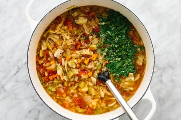 Stirring ingredients in a large pot for cabbage soup.