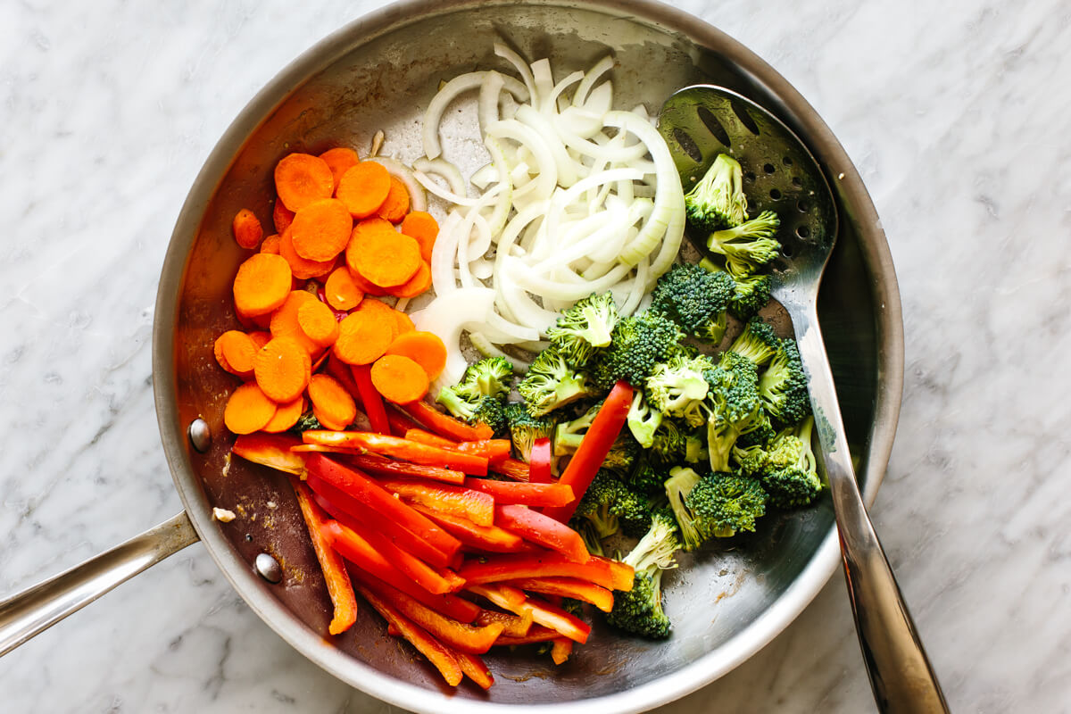 Sauteeing vegetables in a pan for chicken stir-fry.