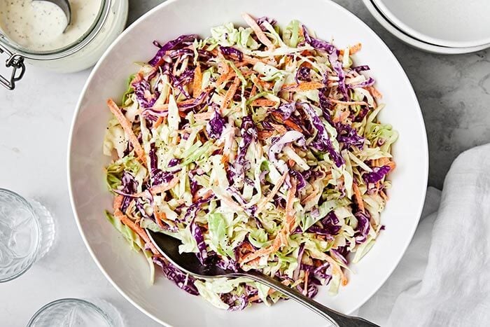 A bowl of coleslaw with a spoon.