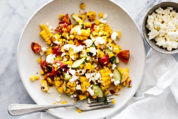 A plate of corn salad with feta cheese