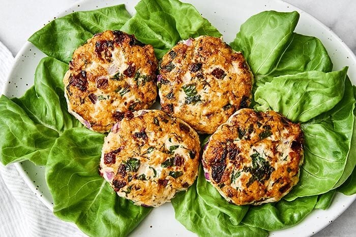 A plate of lettuce and chicken burger patties.