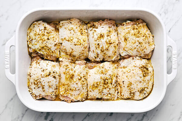 A white baking dish of Greek lemon chicken