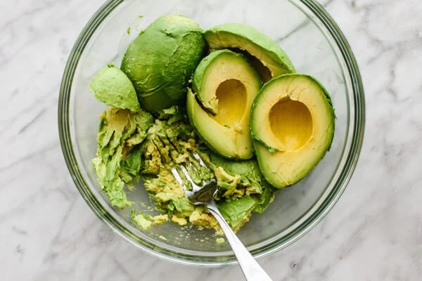 Scooped avocado in a mixing bowl.