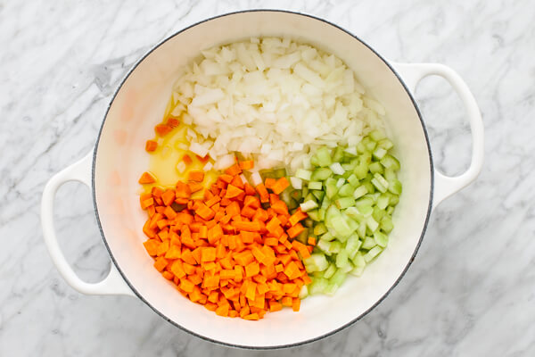 Sauteeing onions, celery, and carrots for a lentil soup in a pot.