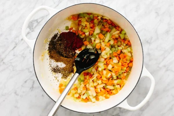 Adding spices into a pot for lentil soup.