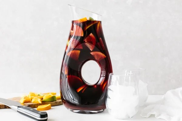 Adding sangria ingredients to a pitcher.