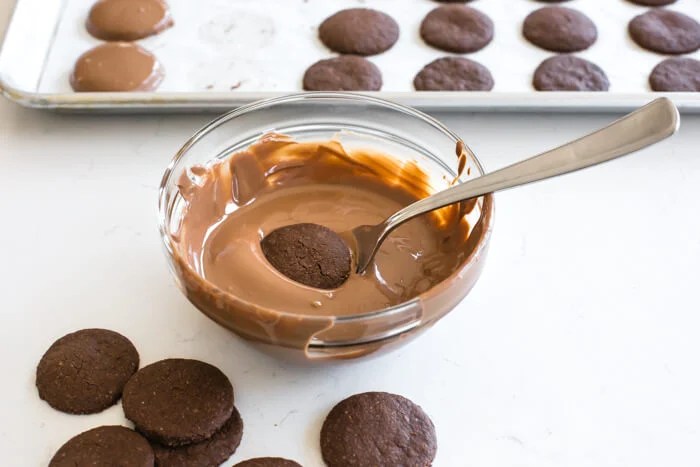 Dipping cookie in chocolate glaze.