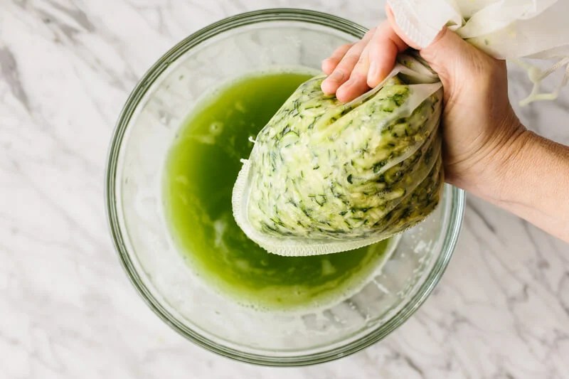 Squeezing the liquid from the zucchini with a nut milk bag.