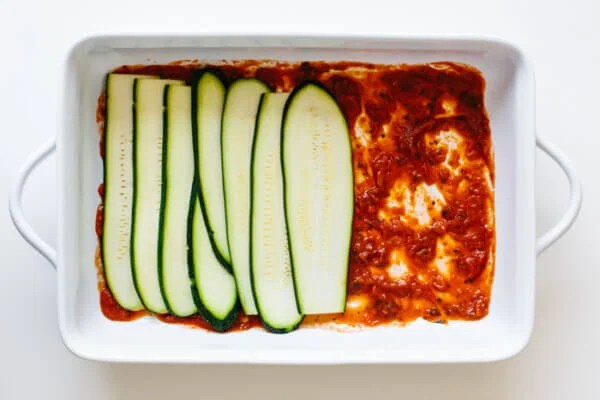 Layering pasta sauce and zucchini for lasagna