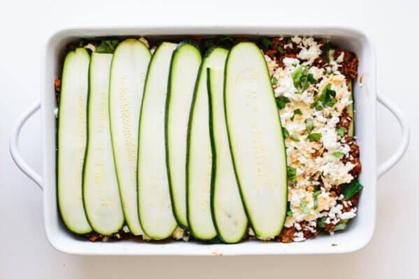 Layering a zucchini lasagna in baking dish