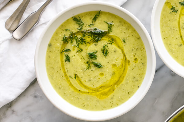 A bowl of zucchini soup next to a napkin