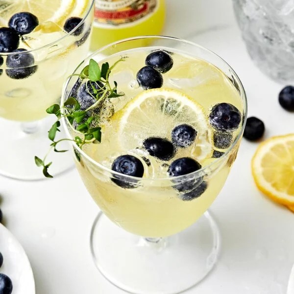 A glass of limoncello prosecco with blueberries.