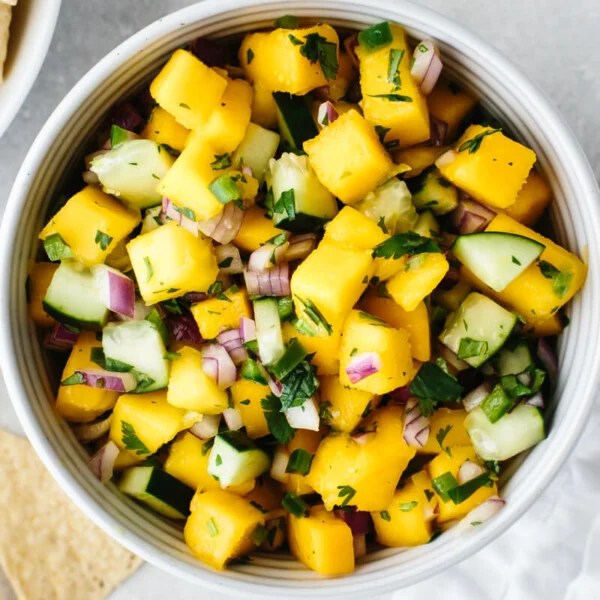 Mango salsa in a bowl with chips on the table.