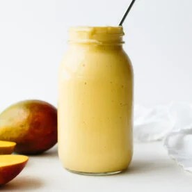 A mango smoothie next to mangos