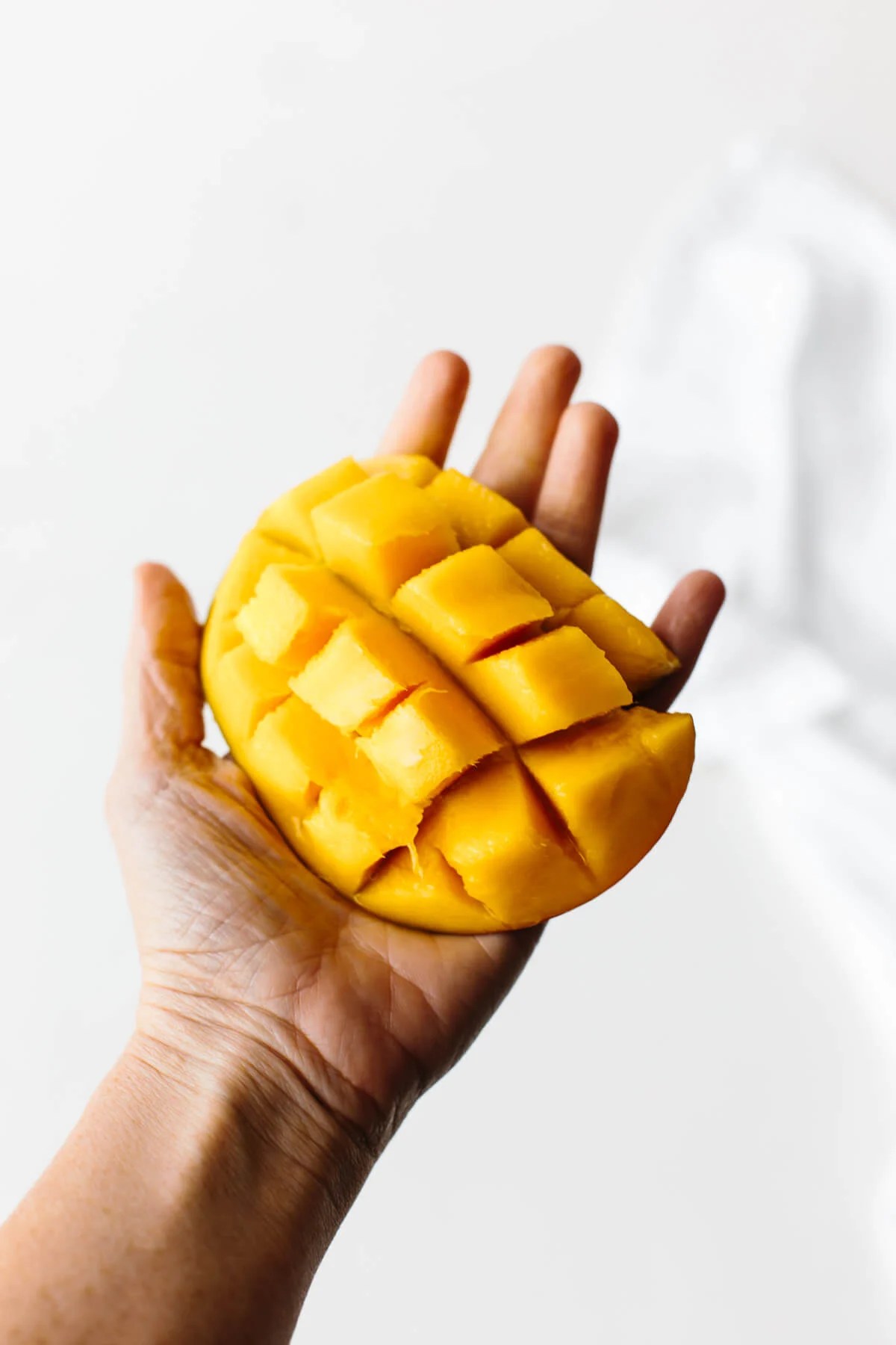 Holding a sliced mango for mango smoothie