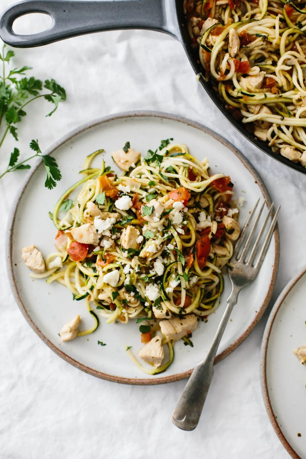 Zucchini noodles with chicken and pico de gallo on a white plate.