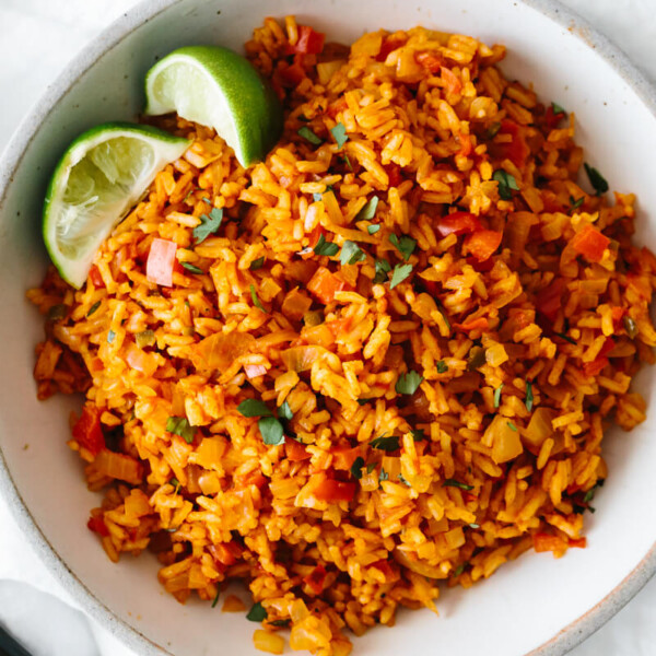 Mexican rice in a bowl with lime wedges.