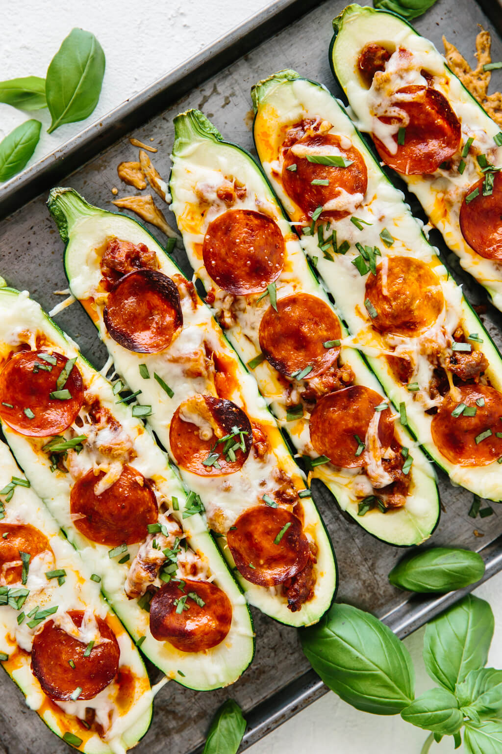 Pizza stuffed zucchini on a baking tray after being cooked.