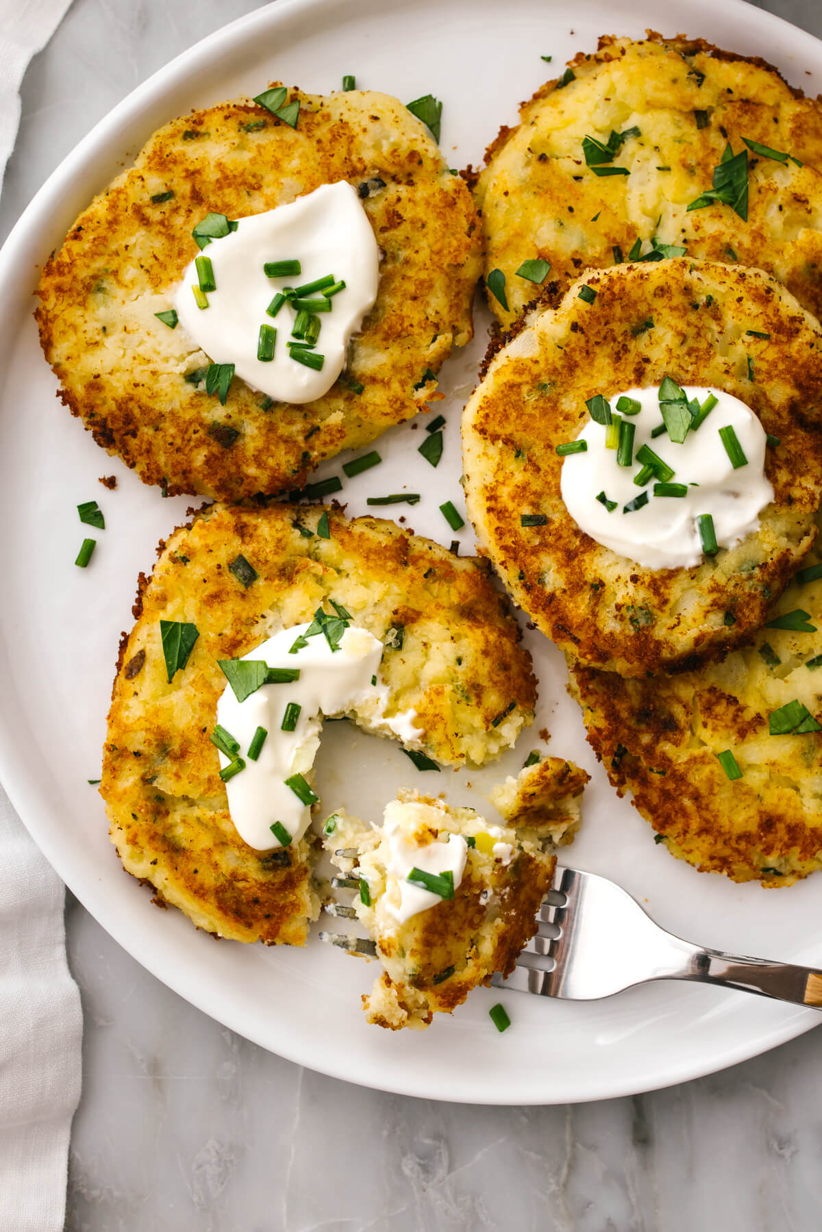 A plate of potato pancakes with a fork.