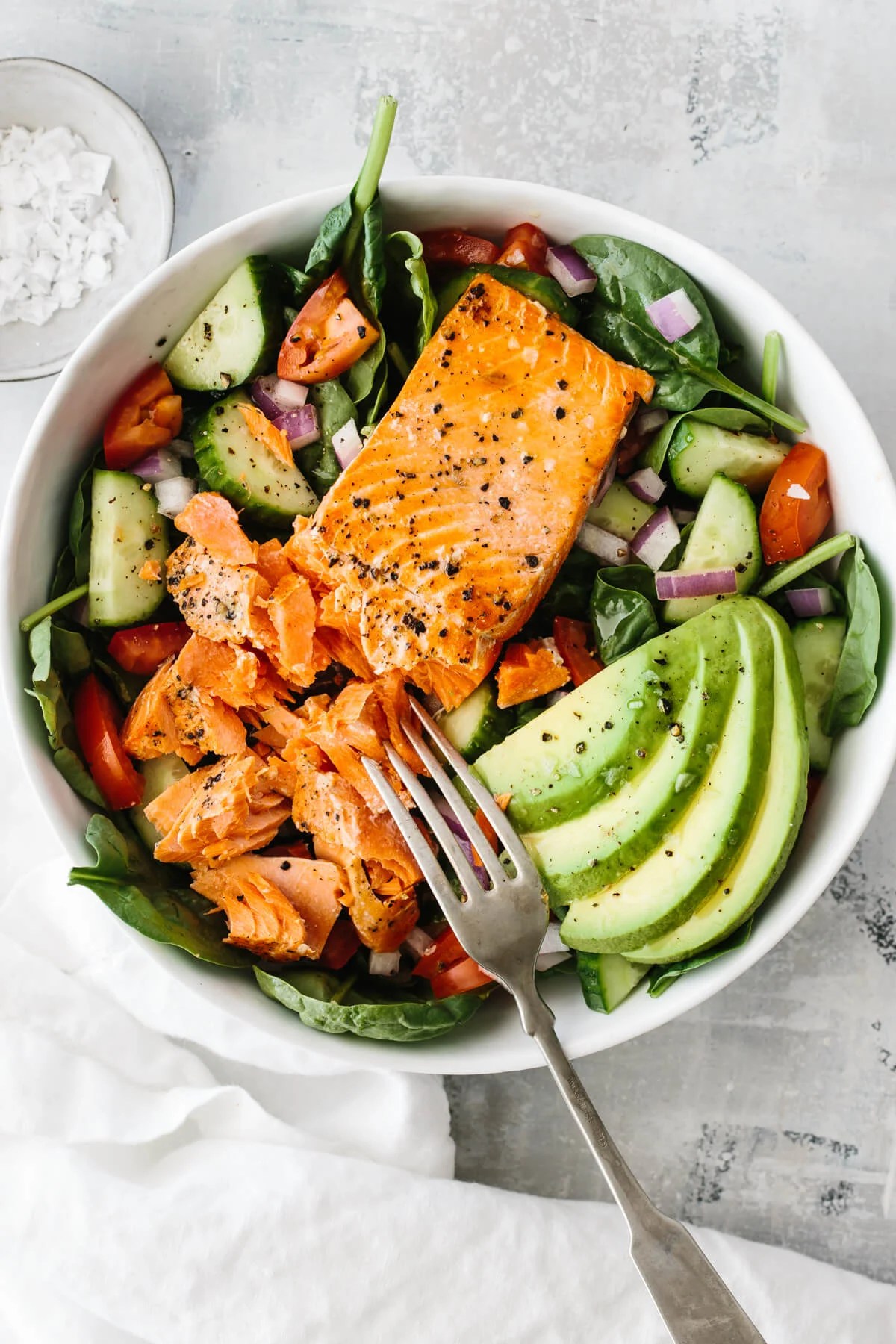 Salmon filet on salad with avocado slices.