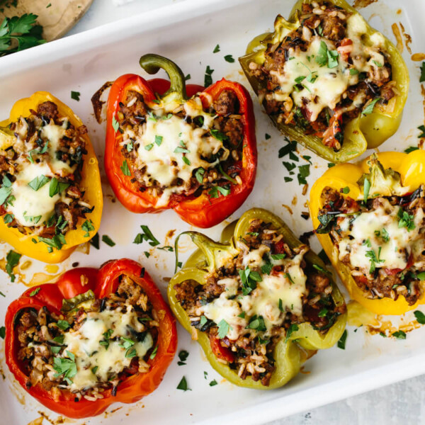 Several stuffed peppers of different colors in a white baking pan.