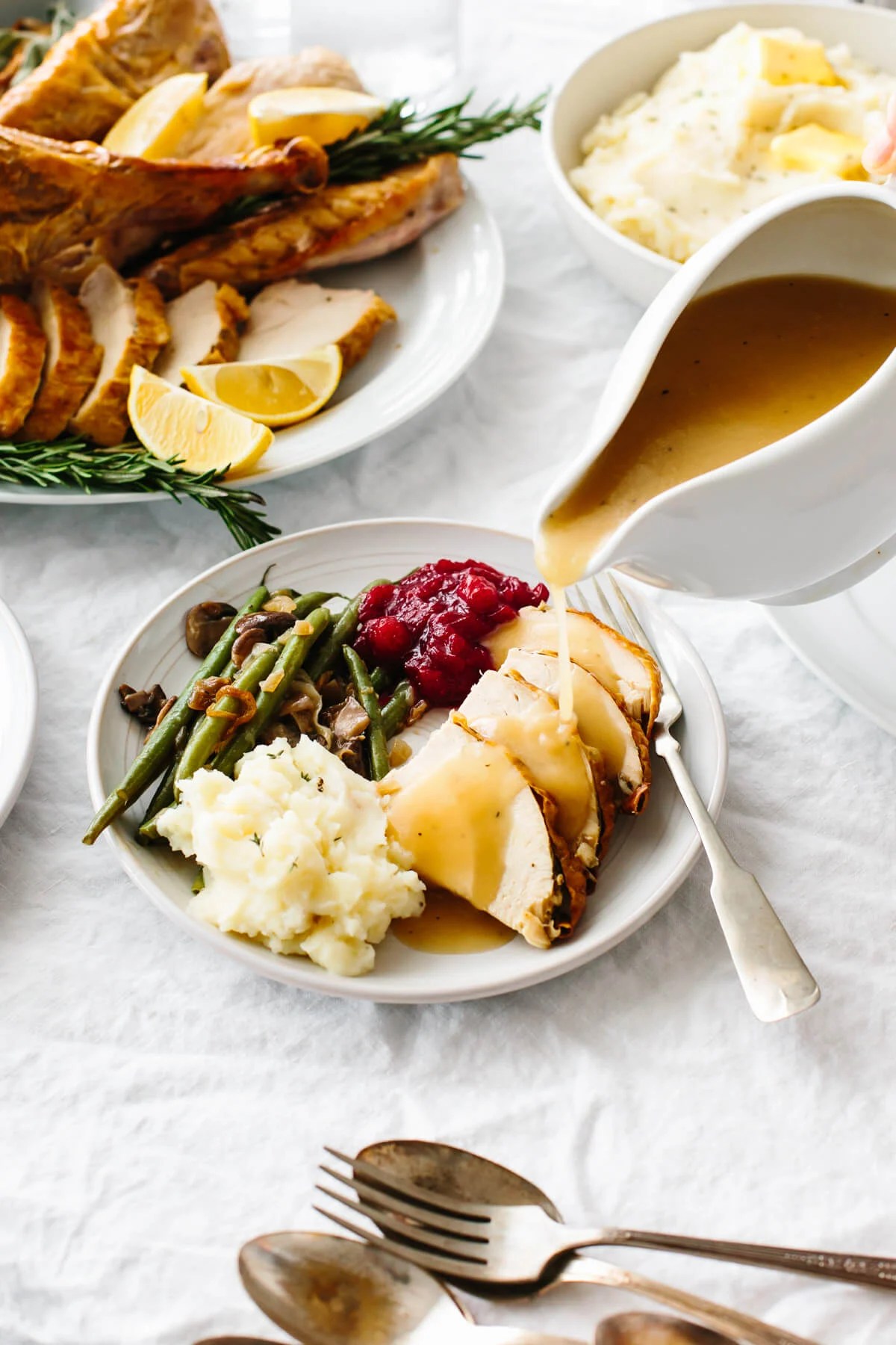 Turkey gravy pouring over a plate of Thanksgiving food.