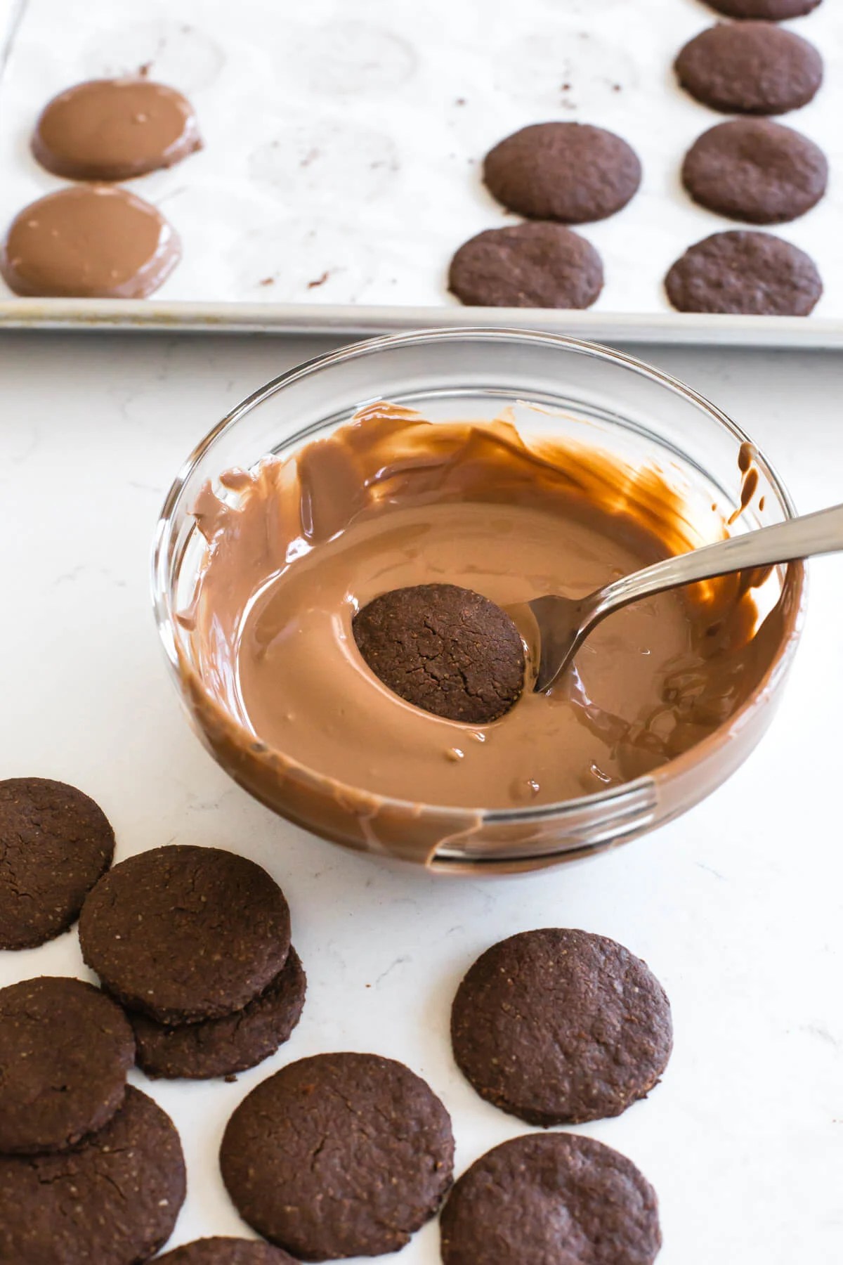 Dipping cookies into a chocolate glaze.