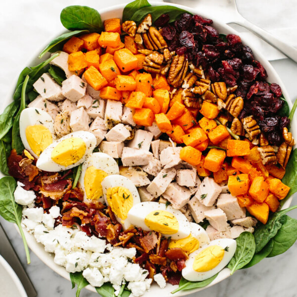 A large bowl with turkey cobb salad next to a vinaigrette bowl.